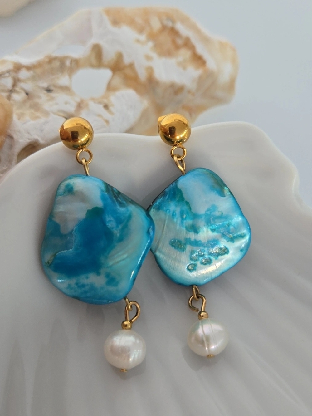 Earrings made of mother-of-pearl, pearls, and gold-plated stainless steel.